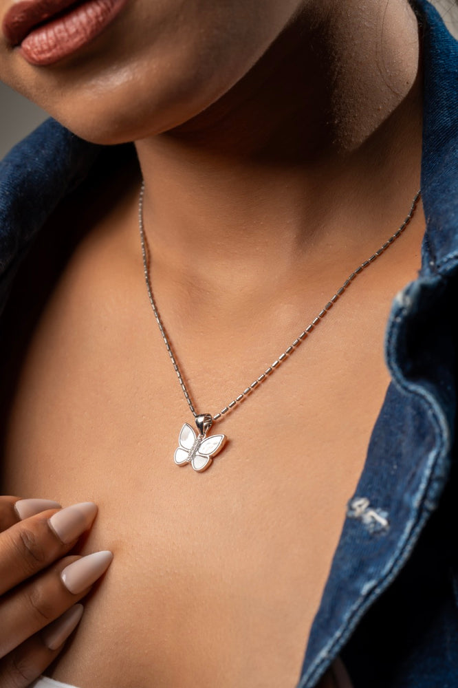 Woman wearing Klarity’s pearl butterfly necklace with a sundress for brunch