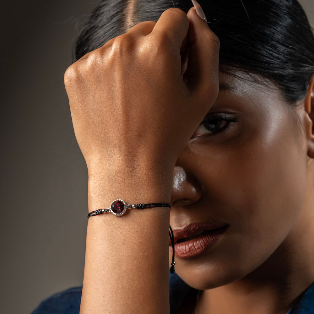 Black cord bracelet by Klarity featuring a red cubic zirconia centerpiece
