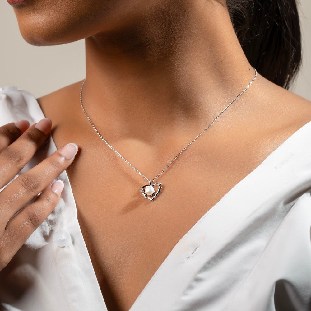 Model wearing Klarity’s  silver pearl heart pendant in white dress - timeless jewellery.
